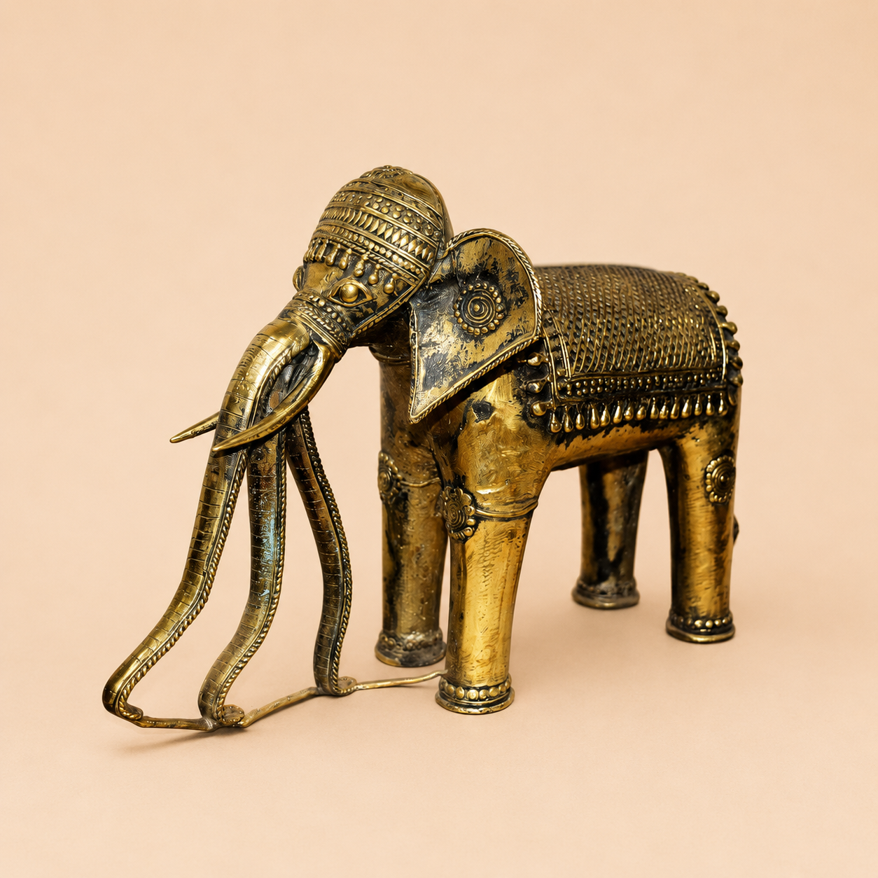 Brass elephant figurine on beige backdrop